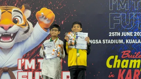 Two young Perak Legends students holding their certificates on the podium